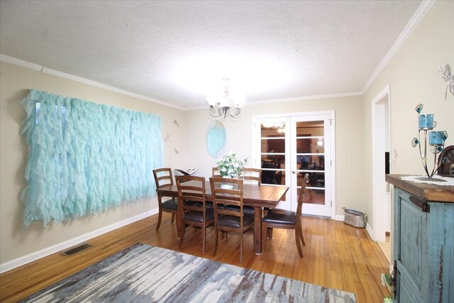 dining space featuring an inviting chandelier, wood-type flooring, and a textured ceiling