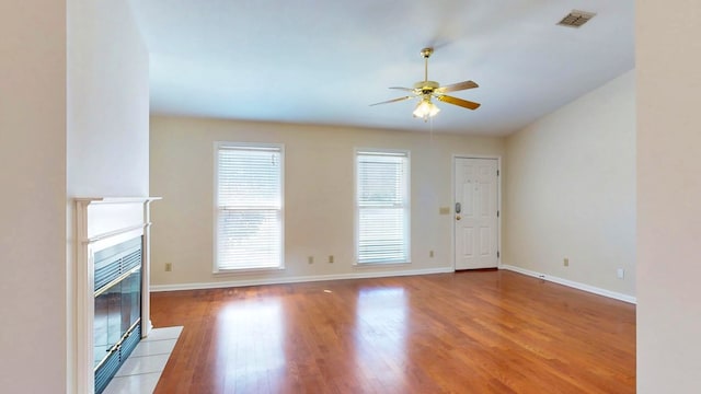 unfurnished living room featuring visible vents, wood finished floors, baseboards, ceiling fan, and a tile fireplace