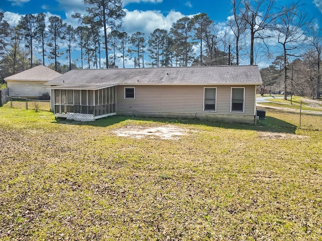 rear view of house with fence, a lawn, and a sunroom