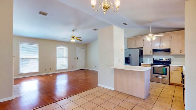 kitchen with visible vents, under cabinet range hood, stainless steel appliances, light tile patterned flooring, and vaulted ceiling