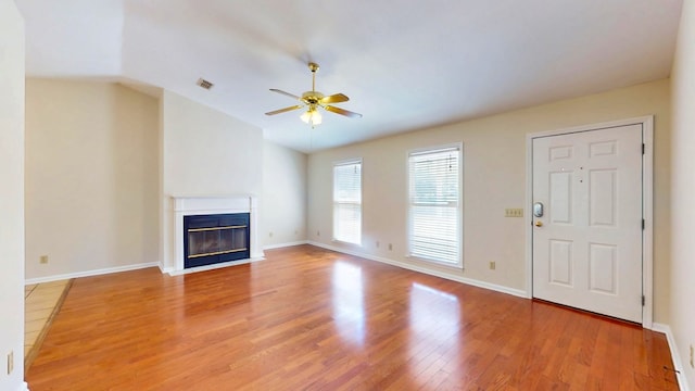 unfurnished living room featuring light wood-type flooring, a fireplace with flush hearth, visible vents, ceiling fan, and vaulted ceiling