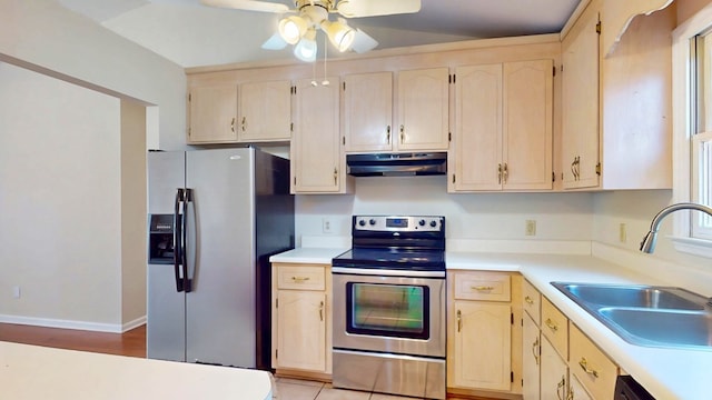 kitchen with under cabinet range hood, appliances with stainless steel finishes, light countertops, and a sink