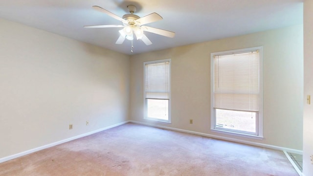 spare room with ceiling fan, light colored carpet, and baseboards