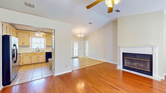 kitchen featuring a sink, light countertops, stainless steel refrigerator with ice dispenser, dishwasher, and open floor plan