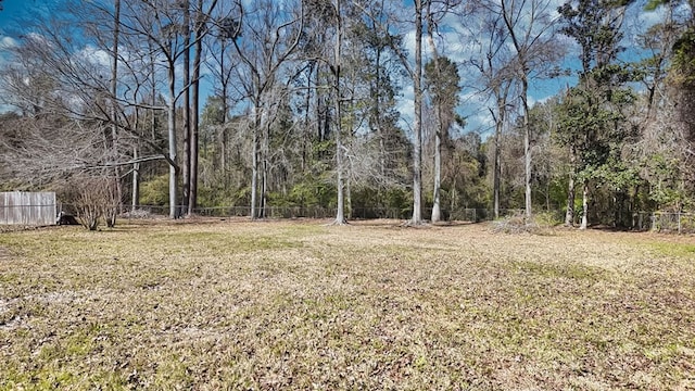 view of yard featuring fence and a wooded view