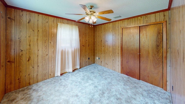 2001 Redfearn St, Barwick, GA 31720 - unfurnished bedroom featuring wood walls, carpet flooring, crown molding, a closet, and ceiling fan