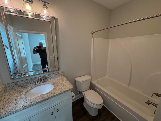 bathroom with toilet, wood finished floors, vanity, shower / washtub combination, and baseboards