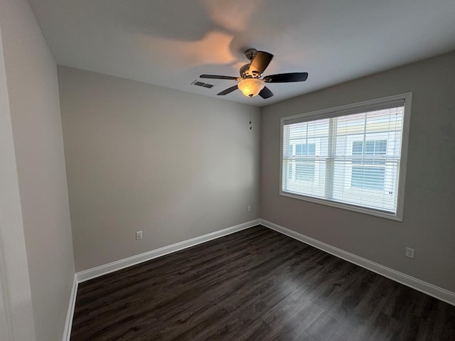 unfurnished room featuring dark wood-style flooring, a ceiling fan, and baseboards