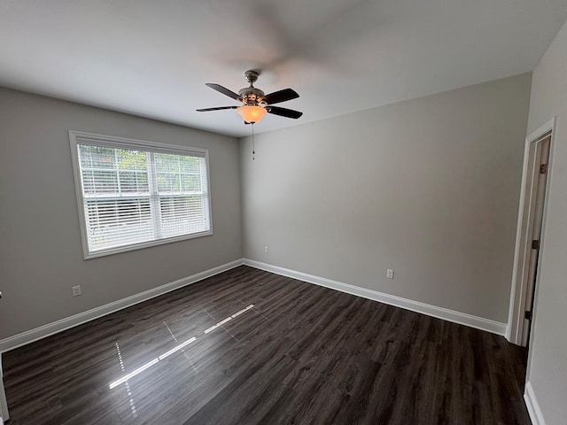 unfurnished room featuring dark wood-style floors, a ceiling fan, and baseboards