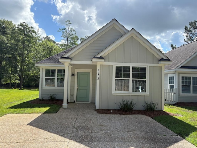 bungalow with board and batten siding, a front lawn, and roof with shingles