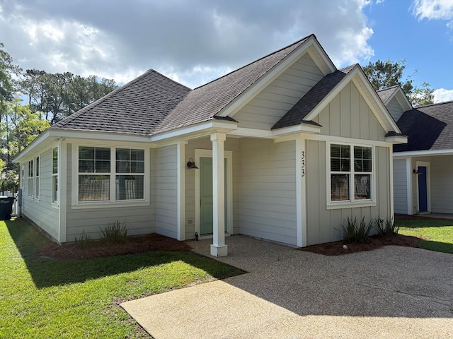 bungalow-style house featuring board and batten siding, a shingled roof, and a front yard