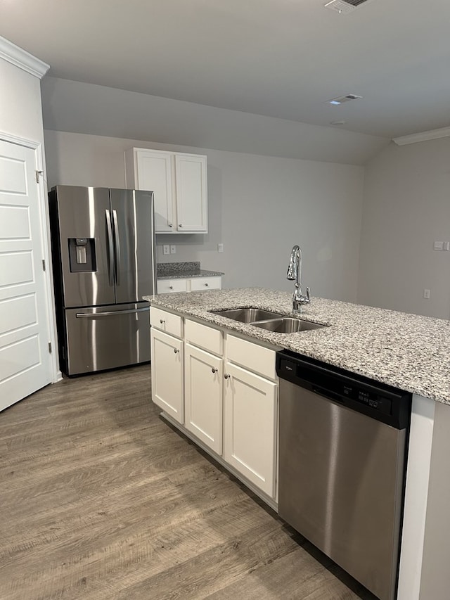 kitchen featuring sink, hardwood / wood-style flooring, appliances with stainless steel finishes, white cabinetry, and light stone countertops