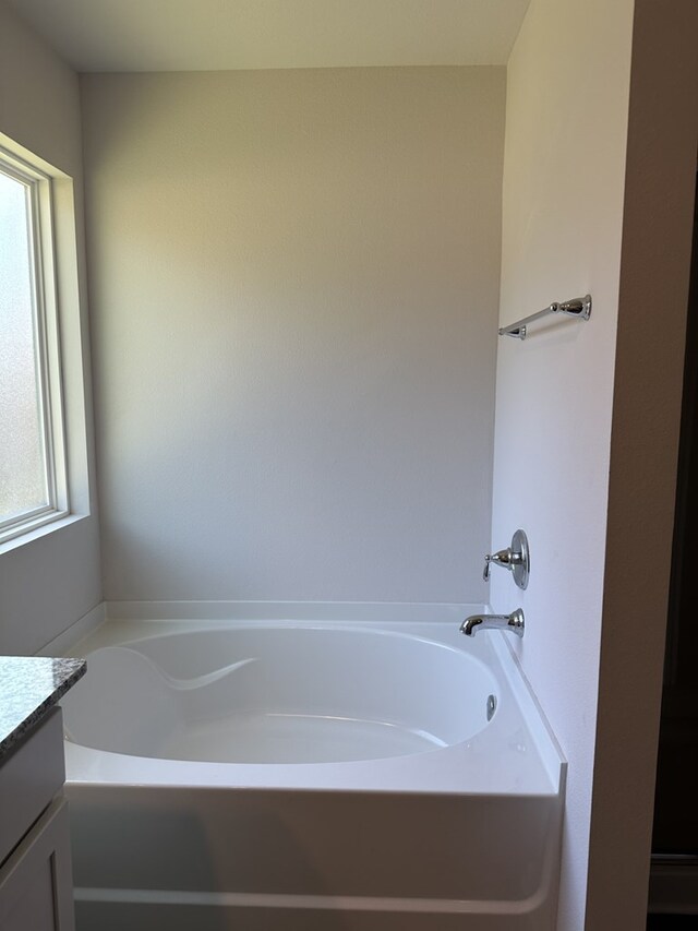 bathroom featuring a tub to relax in, a healthy amount of sunlight, and vanity