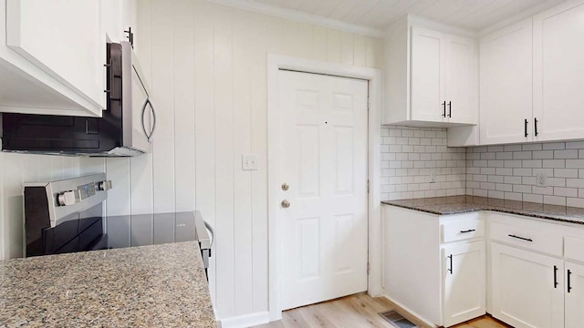 712 Young St, Thomasville, GA 31792 - kitchen featuring dark stone counters, stainless steel microwave, electric range, decorative backsplash, and white cabinetry