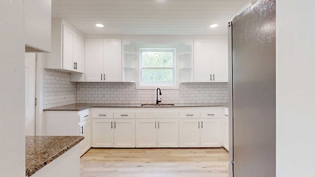 712 Young St, Thomasville, GA 31792 - kitchen with dark stone countertops, freestanding refrigerator, white cabinetry, open shelves, and light wood-style flooring