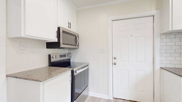 712 Young St, Thomasville, GA 31792 - kitchen featuring appliances with stainless steel finishes, white cabinets, light stone counters, and light wood-type flooring
