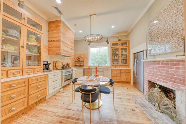 kitchen with decorative backsplash, ornamental molding, stainless steel appliances, a brick fireplace, and light wood-type flooring