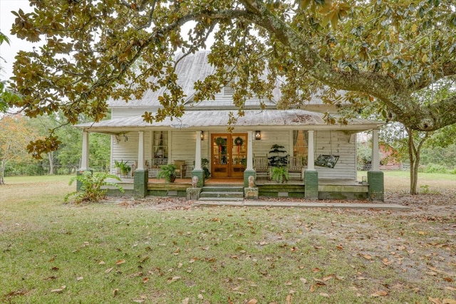 farmhouse-style home featuring french doors, a porch, and a front yard