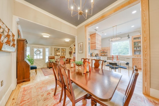 dining space featuring ornamental molding, a chandelier, and light hardwood / wood-style flooring