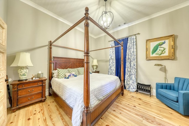 bedroom with an inviting chandelier, ornamental molding, and light hardwood / wood-style floors