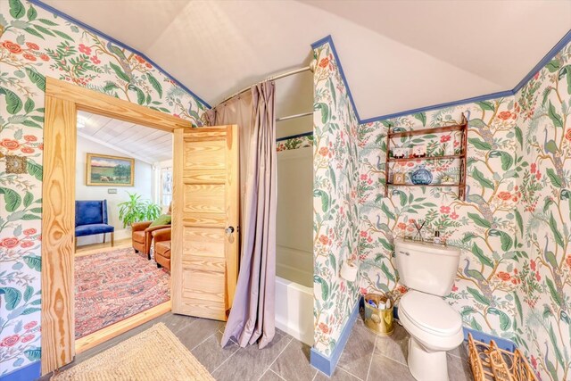 bathroom featuring vaulted ceiling, tile patterned floors, toilet, and shower / bath combo with shower curtain