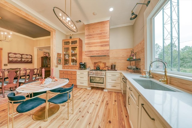 kitchen featuring pendant lighting, sink, high end range, crown molding, and light wood-type flooring