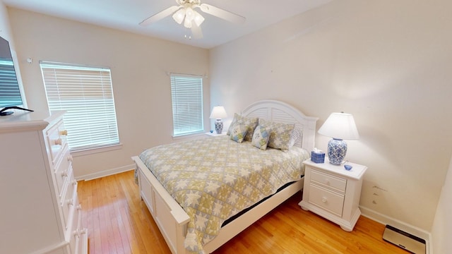 bedroom featuring ceiling fan, a baseboard radiator, and light wood-type flooring