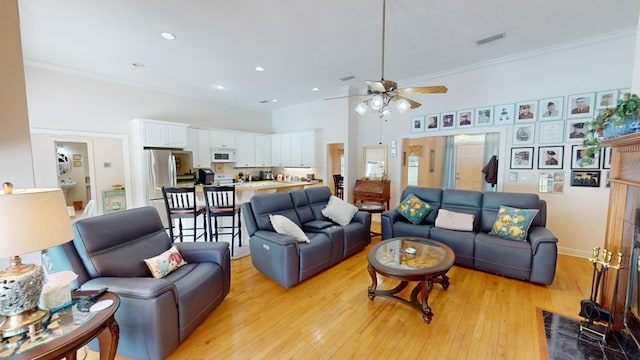 living room with crown molding, ceiling fan, and light hardwood / wood-style flooring