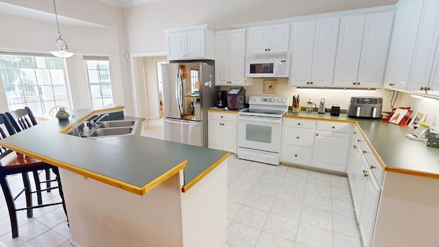 kitchen with white cabinetry, sink, a breakfast bar area, hanging light fixtures, and white appliances