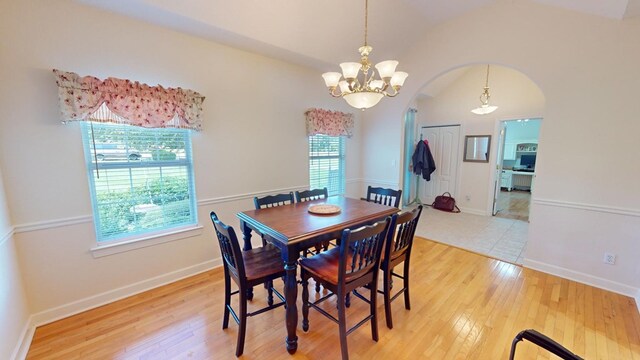 dining room featuring vaulted ceiling, hardwood / wood-style floors, and an inviting chandelier