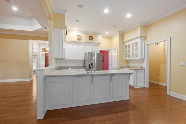 kitchen featuring white cabinetry, stainless steel refrigerator with ice dispenser, wood-type flooring, light stone countertops, and kitchen peninsula