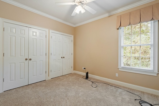 unfurnished bedroom with light carpet, two closets, ornamental molding, and ceiling fan