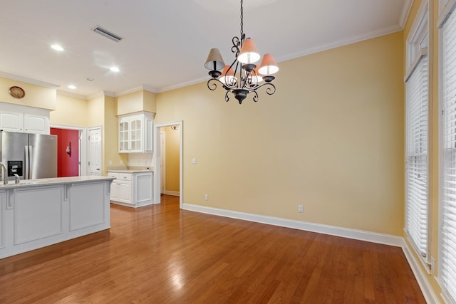 kitchen with white cabinetry, crown molding, hardwood / wood-style flooring, and stainless steel refrigerator with ice dispenser