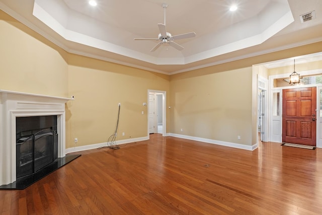 unfurnished living room with hardwood / wood-style flooring, ornamental molding, a raised ceiling, and ceiling fan