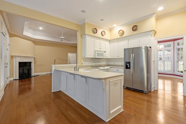 kitchen with white appliances, kitchen peninsula, sink, and white cabinets