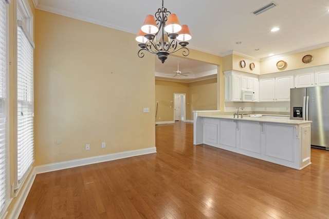 kitchen featuring light wood-type flooring, ornamental molding, stainless steel fridge, pendant lighting, and white cabinets