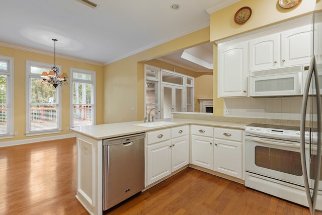 kitchen with sink, pendant lighting, white cabinets, and white appliances