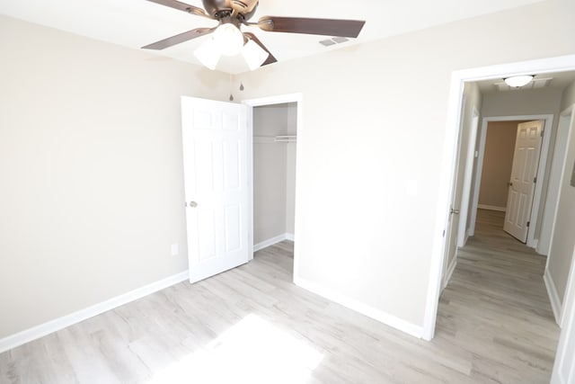 unfurnished bedroom with ceiling fan, light wood-type flooring, and a closet