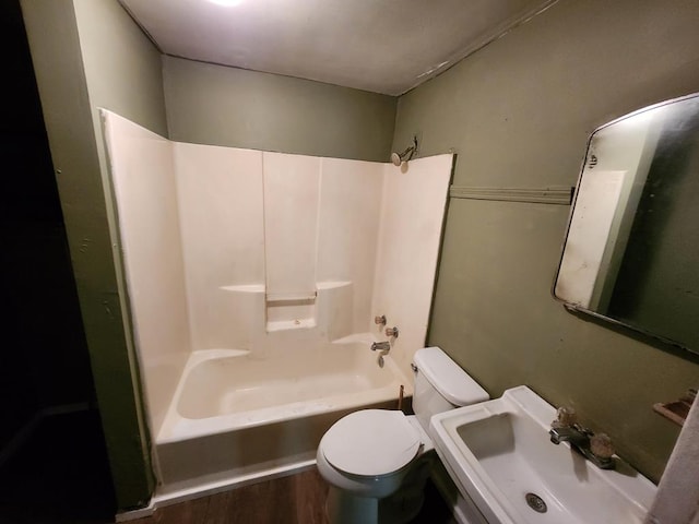 full bath with shower / bathing tub combination, toilet, wood finished floors, and a sink