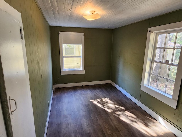 empty room featuring dark wood finished floors, wooden ceiling, and baseboards