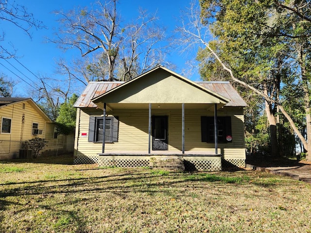 bungalow-style house with metal roof, covered porch, and a front yard