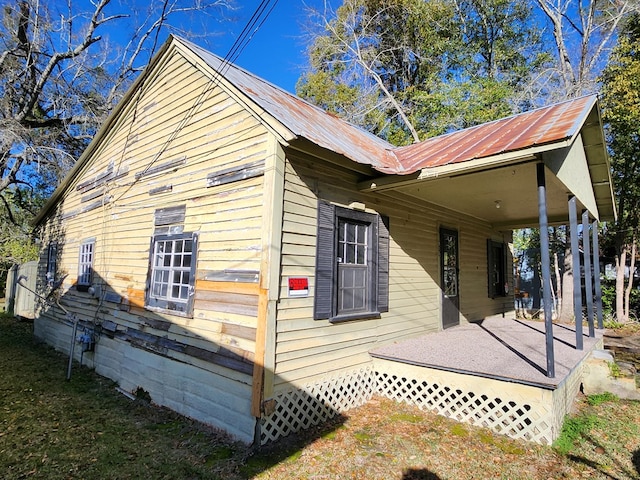 view of home's exterior with metal roof, a yard, and a porch