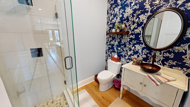 bathroom with hardwood / wood-style flooring, vanity, toilet, and a shower with shower door