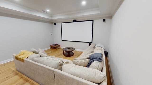 home theater room with crown molding, a raised ceiling, and hardwood / wood-style floors