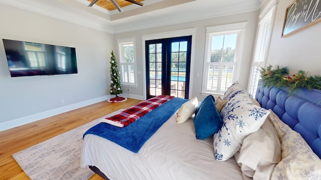 bedroom with crown molding, hardwood / wood-style flooring, a tray ceiling, access to outside, and french doors