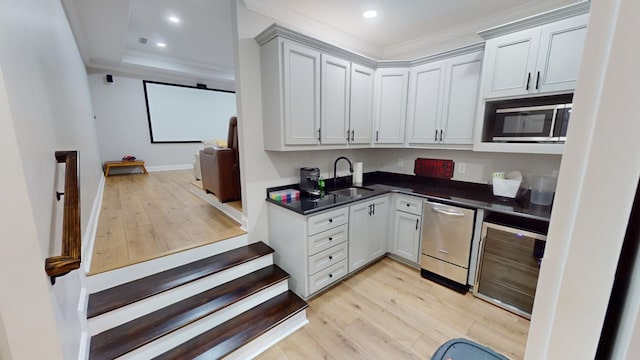 kitchen with sink, stainless steel appliances, wine cooler, ornamental molding, and light wood-type flooring