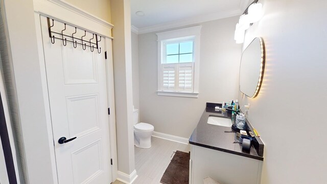 bathroom featuring vanity, hardwood / wood-style floors, crown molding, and toilet