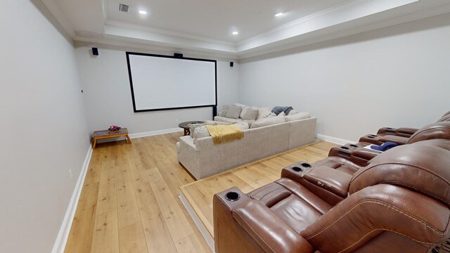 home theater room featuring hardwood / wood-style flooring, ornamental molding, and a raised ceiling