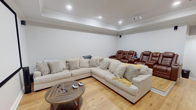 home theater room featuring hardwood / wood-style flooring, crown molding, and a tray ceiling