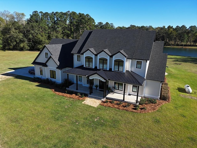 view of front of property with a water view, covered porch, and a front lawn